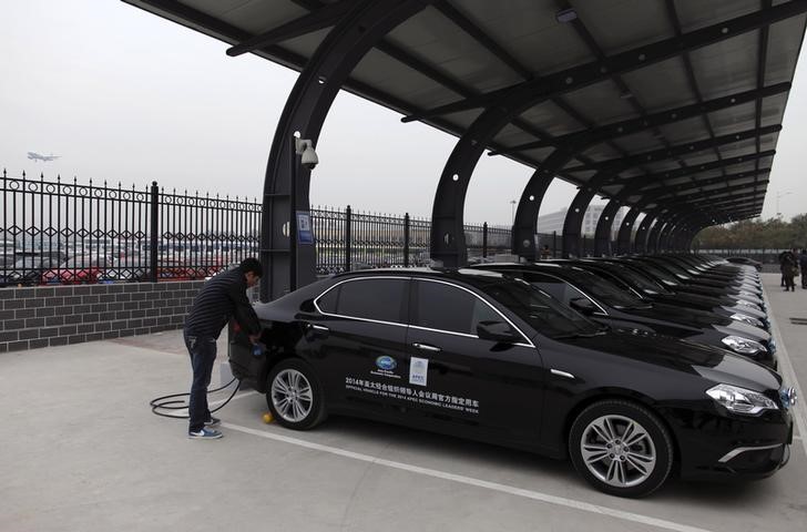 © Reuters. A man charges the batteries of BAIC Motors electric cars, which will be serve as official vehicles for the APEC Summit, at a new charging station at the Beijing Capital International Airport in Beijing
