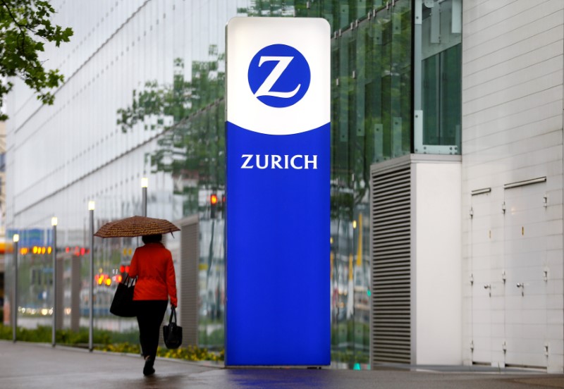 © Reuters. A woman walks past a sign with the logo of Swiss company Zurich insurance is seen at an office building in Zurich's Oerlikon suburb