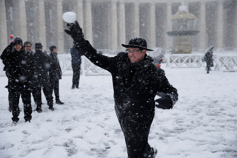 © Reuters. Un prete gioca con la neve in piazza San Pietro