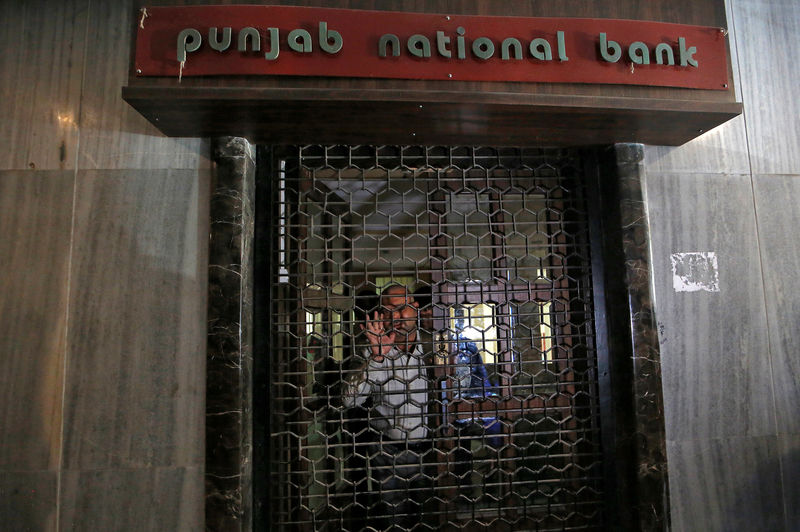 © Reuters. A Central Bureau of Investigation official looks out from a closed door of a Punjab National Bank branch in Mumbai