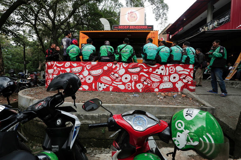 © Reuters. FILE PHOTO: Go-Jek drivers sit as they wait for their orders at a food stall in Jakarta