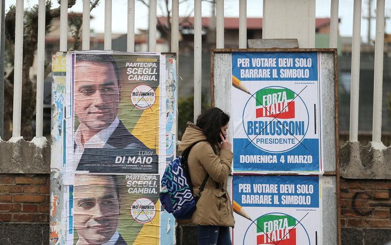 © Reuters. Mulher passa por cartazes de campanha eleitoral em Pomigliano D'Arco, na Itália