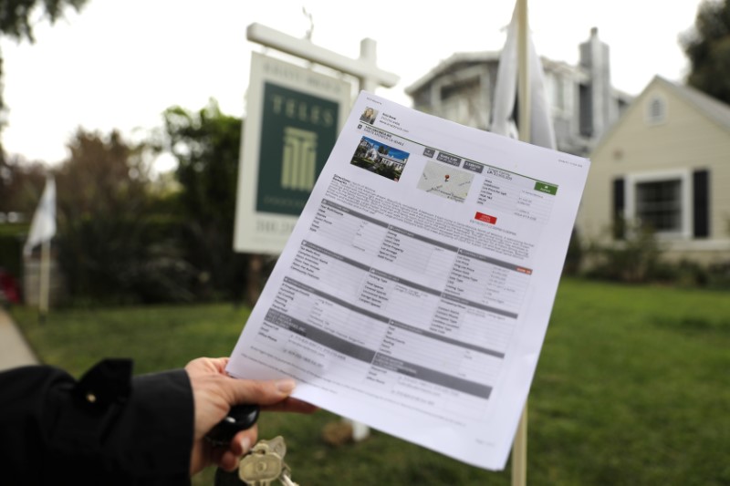 © Reuters. FILE PHOTO: A woman holds a piece of paper advertising a home for sale in Santa Monica