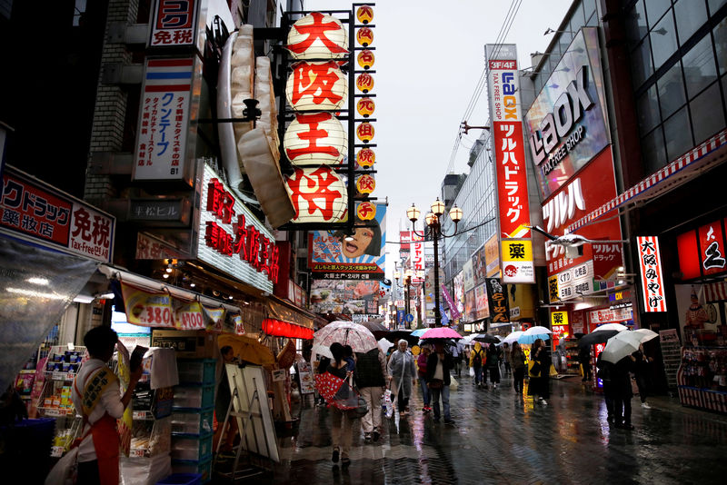 © Reuters. FILE PHOTO: People walk through a shopping district in Osaka