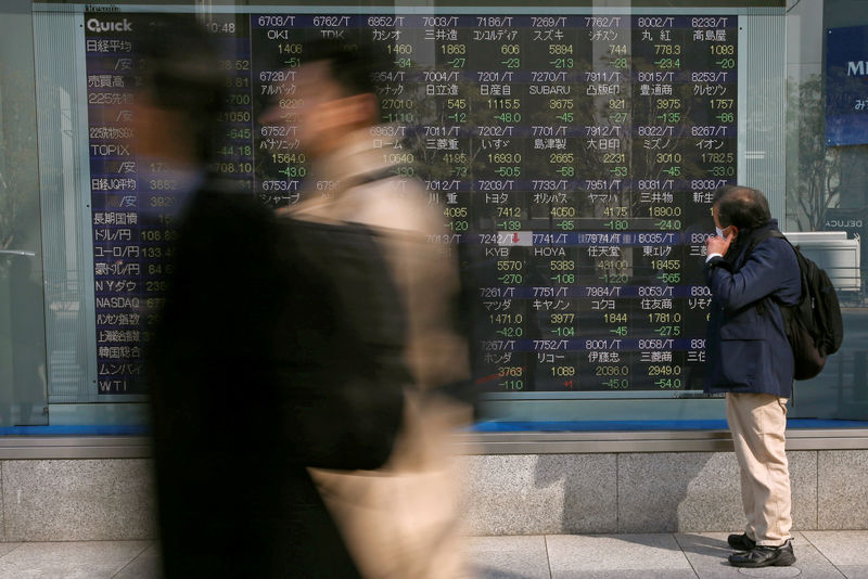 © Reuters. FILE PHOTO - A man looks at an electronic stock quotation board outside a brokerage in Tokyo