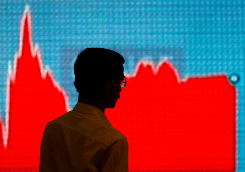 © Reuters. A man walks past a screen displaying news of markets update inside the Bombay Stock Exchange (BSE) building in Mumbai