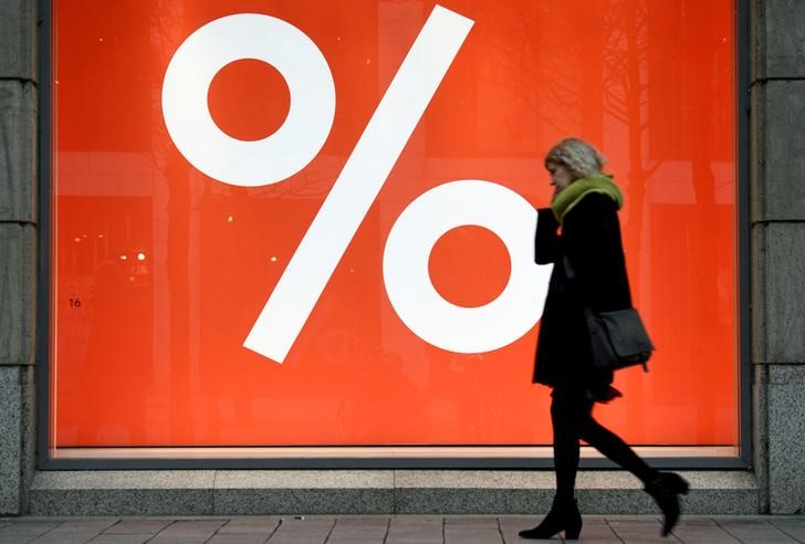 © Reuters. FILE PHOTO: A woman passes a sale sign in a shop window in downtown Hamburg