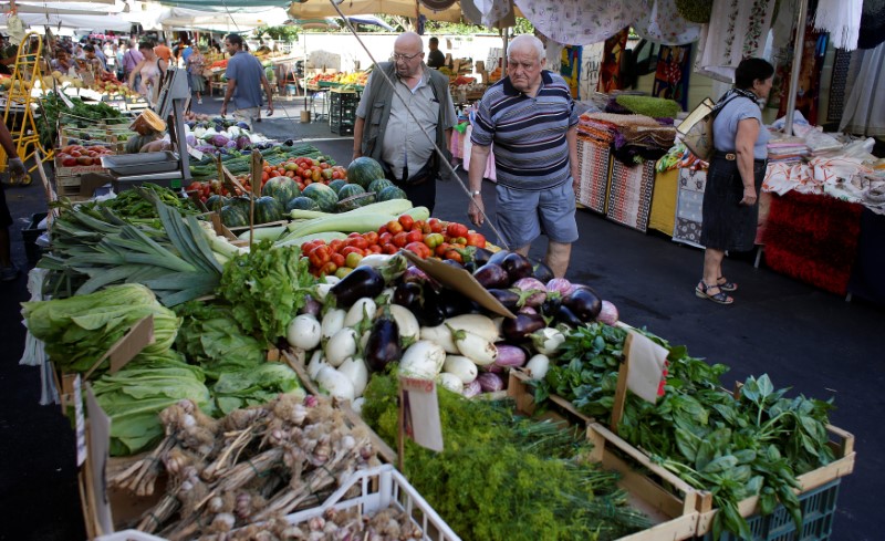 © Reuters. People check fruit and vegetables in a street market in Rome