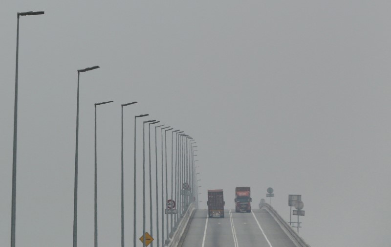 © Reuters. Lorries cross a bridge in Klang, Malaysia