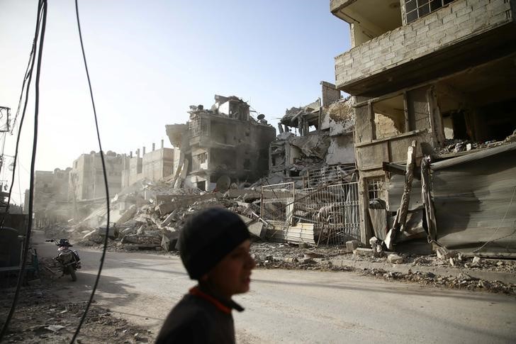 © Reuters. A boy walks near damaged buildings in the besieged town of Douma in eastern Ghouta in Damascus