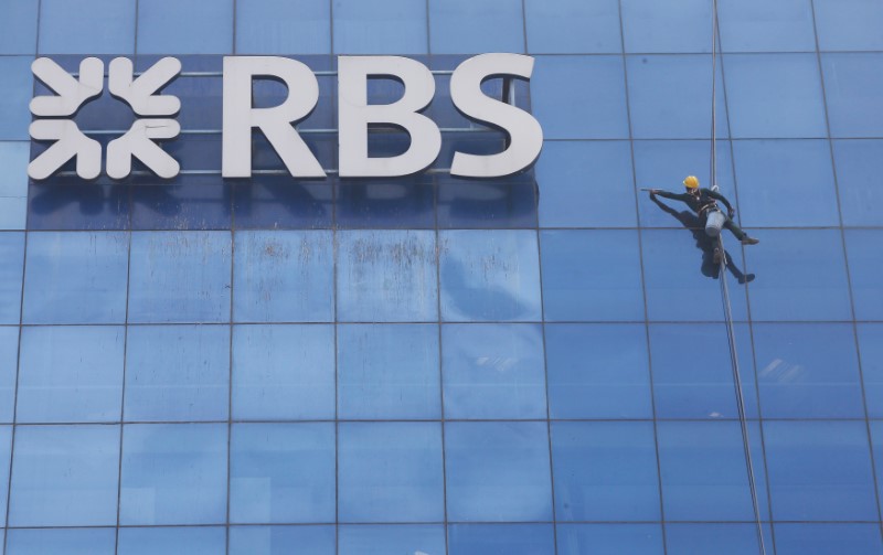 © Reuters. FILE PHOTO: Worker cleans the glass exterior next to the logo of RBS (Royal Bank of Scotland) bank at a building in Gurugram