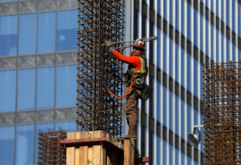 © Reuters. FILE PHOTO - A construction laborer works high atop a building in down town Los Angeles