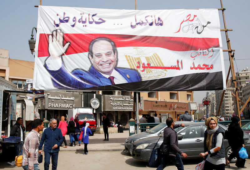 © Reuters. Pessoas caminham diante de poster do presidente do Egito Abdel Fattah al-Sisi