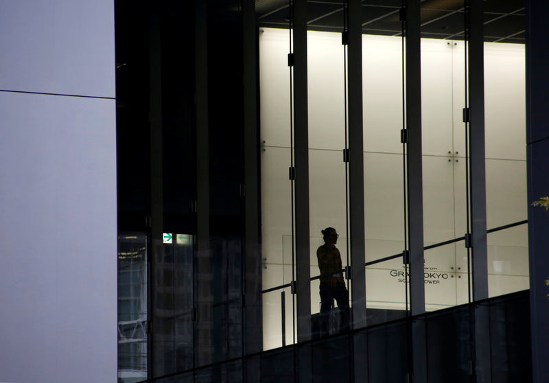 © Reuters. Man is silhouetted against commercial building at a business district in Tokyo
