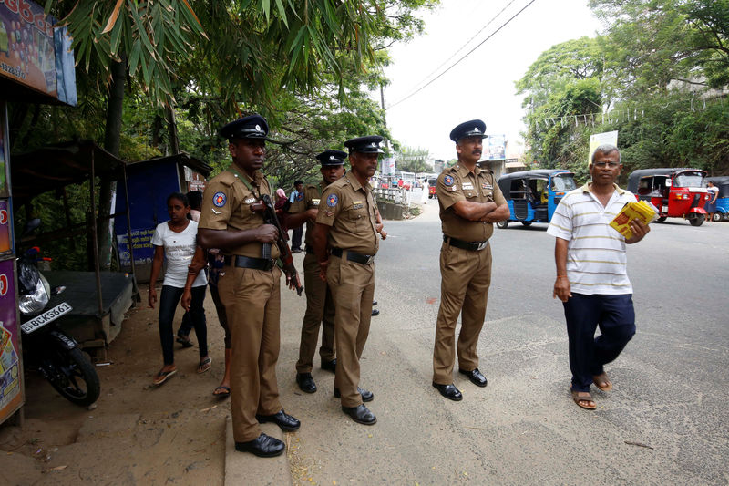 © Reuters. Sri Lanka's police officers stand guard on a main road after a clash between two communities in Digana