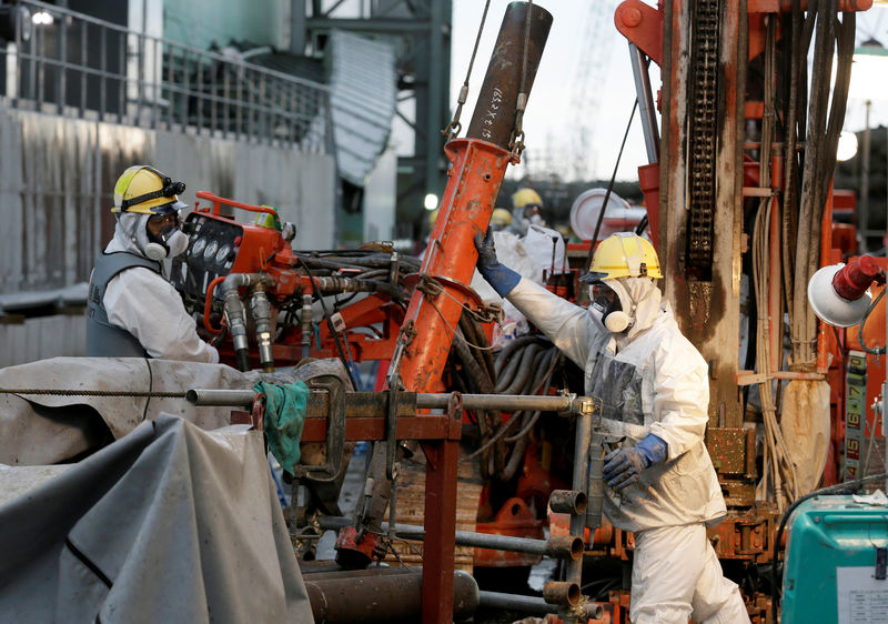 © Reuters. FILE PHOTO: Workers prepare frozen pipes during operations to construct an underground ice wall at Tepco's tsunami-crippled Fukushima Daiichi nuclear power plant