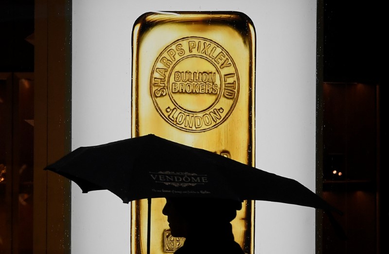 © Reuters. A pedestrian walks past a window displaying a representation of a gold bar at a bullion broker in Piccadilly, London, Britain