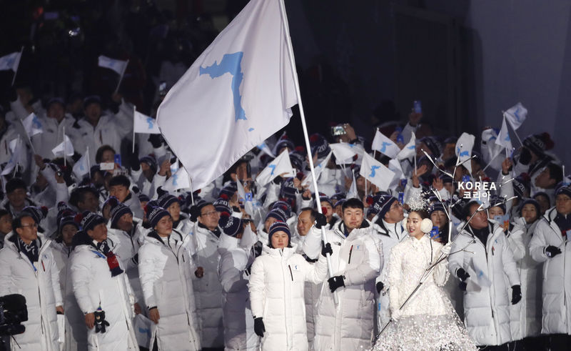 © Reuters. Hwang Chung Gum e Won Yunjong da Coreia carregam bandeira unificada durante cerimônia de abertura da Olimpíada de Inverno de Pyeongchang