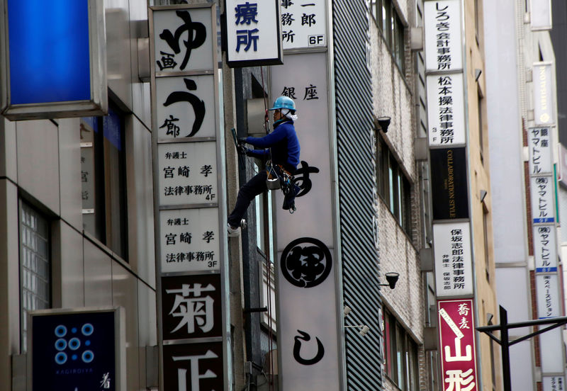 © Reuters. Worker cleans a window of a building at a shopping district in Tokyo