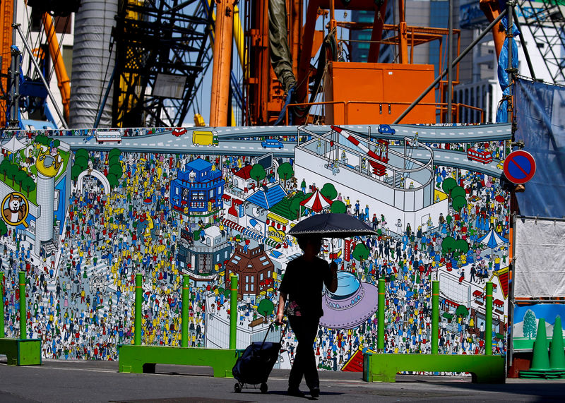 © Reuters. FILE PHOTO: Excavators and heavy equipment rise behind a fence surrounding a construction site in the Shibuya district in Tokyo