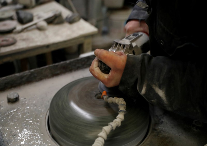 © Reuters. FILE PHOTO: Factory worker Danny Bodie smoothes a curling stone in Kays Factory in Mauchline, Scotland