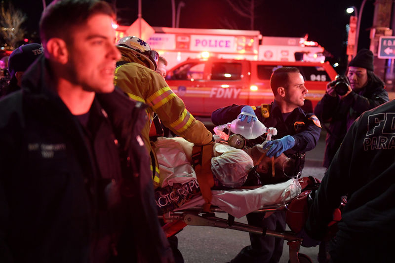 © Reuters. Paramédicos e membros do corpo de bombeiros prestam socorro a vítima de queda de helicóptero em Nova York