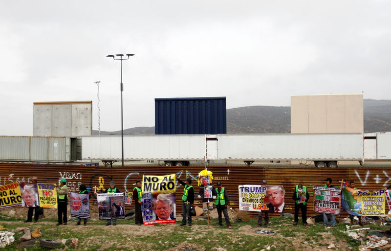 © Reuters. Pessoas seguram cartazes em protesto contra muro proposto por Trump em Tijuana