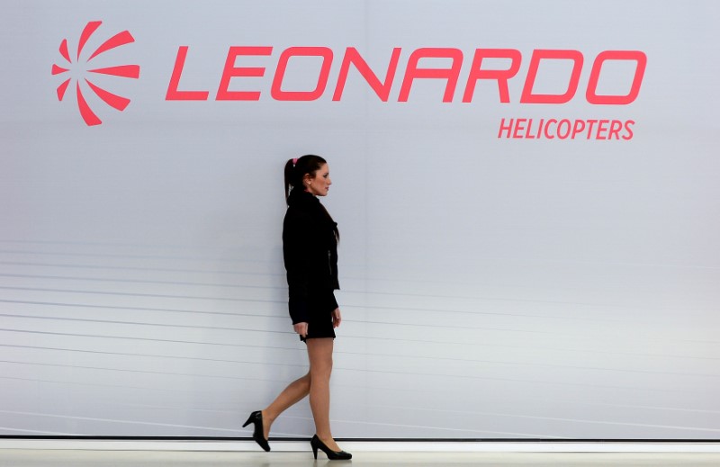 © Reuters. A hostess walks past a Leonardo's helicopters logo at the headquarters in Vergiate