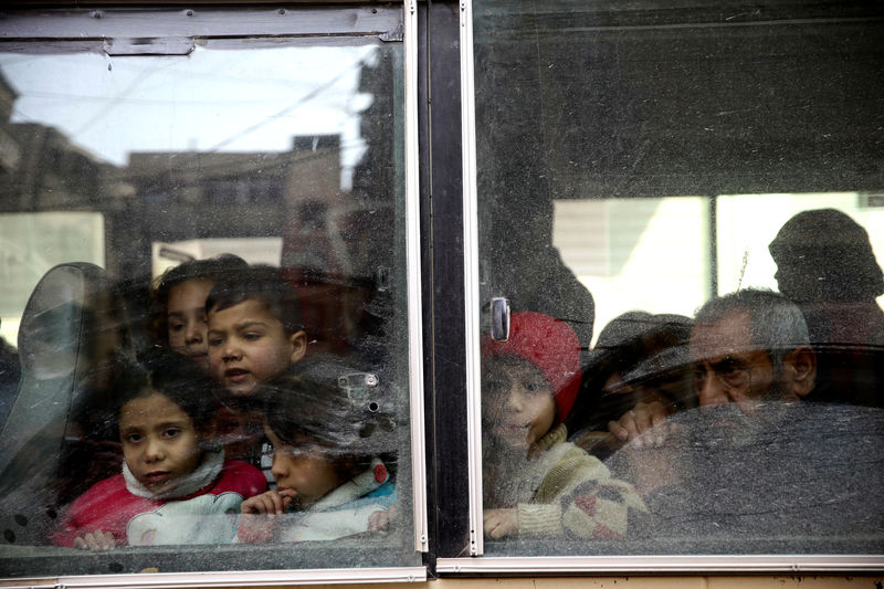 © Reuters. Crianças olham através de janela de ônibus enquanto deixam cidade de Douma, em Ghouta Oriental, na Síria