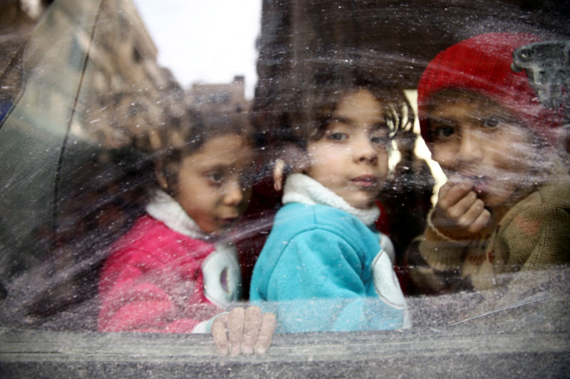 © Reuters. Children look through a bus window during evacuation from the besieged town of Douma