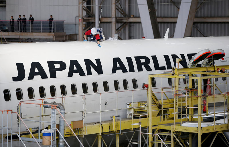 © Reuters. A maintenance worker is seen atop of an airplane of Japan Airlines at a hangar of Haneda airport in Tokyo