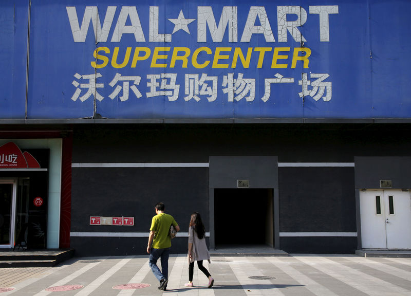 © Reuters. FILE PHOTO: Pedestrians walk past a signboard of Wal-Mart at its branch store in Beijing