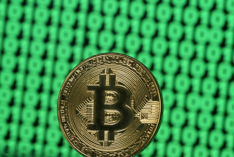 © Reuters. FILE PHOTO: Bitcoin token is seen placed on a monitor that displays binary digits in this illustration picture