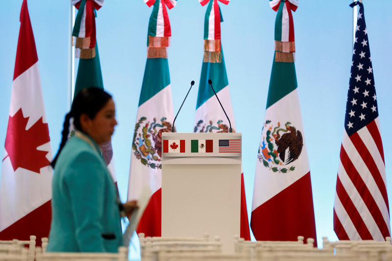 © Reuters. A woman walks by the flags of Canada, Mexico and the U.S. before a joint news conference on the closing of the seventh round of NAFTA talks in Mexico City