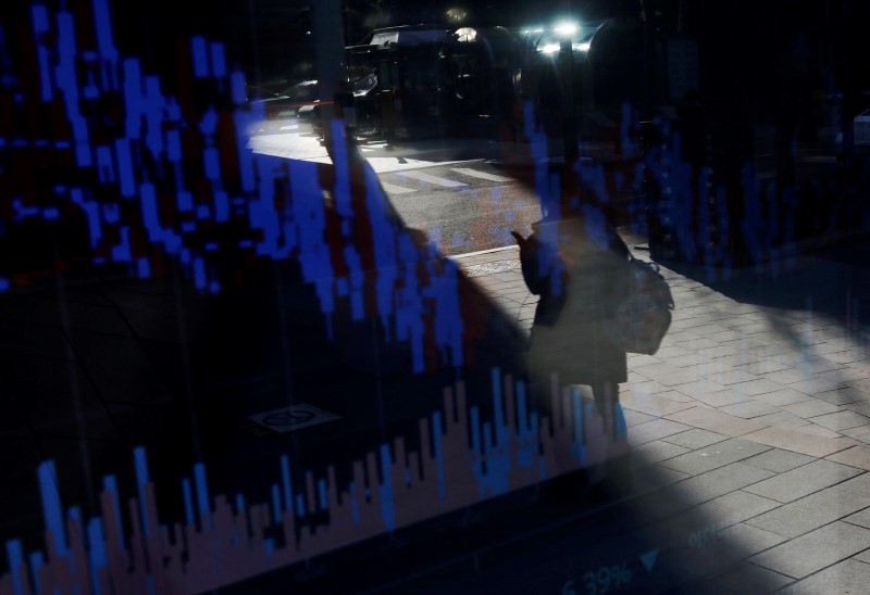 © Reuters. A woman using her mobile phone is reflected on an electric board showing exchange rates of various cryptocurrencies at Bithumb cryptocurrencies exchange in Seoul