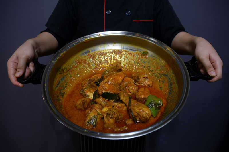 © Reuters. A chef poses with a pot of chicken rendang at a restaurant in Cyberjaya