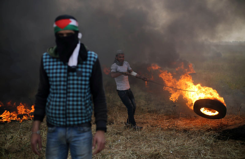 © Reuters. Manifestante palestino move pneu em chamas durante confronto com soldados israelenses na fronteira entre Israel e Gaza