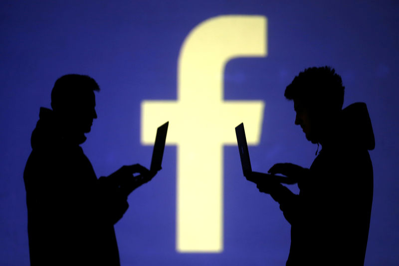 © Reuters. Una ilustración muestra siluetas de usuarios de laptop cerca de una pantalla donde se proyecta el logo de Facebook