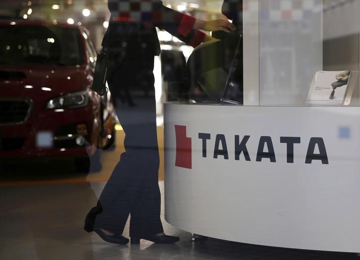 © Reuters. FILE PHOTO: A woman stands next to a logo of Takata Corp at a showroom for vehicles in Tokyo