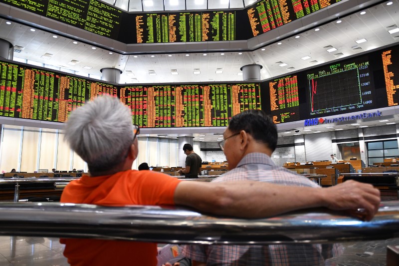 © Reuters. People look at trading boards at a private stock market gallery in Kuala Lumpur