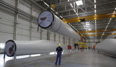 © Reuters. A worker looks at a wing which is being mechanically lifted at the Nordex wind turbine factory hall in Rostock