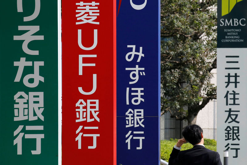© Reuters. FILE PHOTO: A man walks past signboards of Sumitomo Mitsui Banking Corporation, Mizuho Bank, MUFG Bank, and Resona Bank in Tokyo