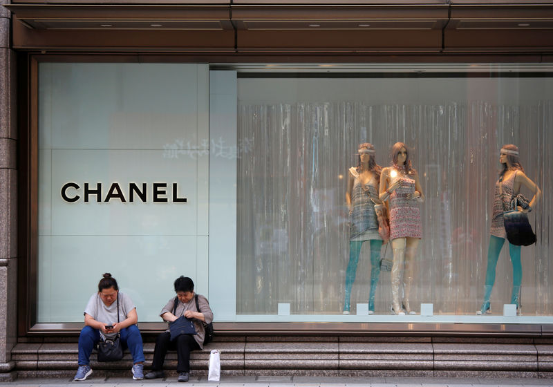 © Reuters. Women sit in front of a Chanel store in Tokyo