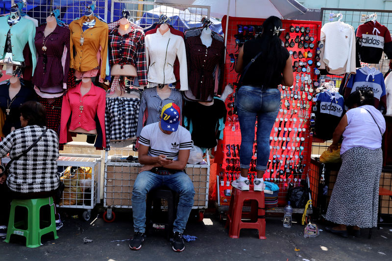 © Reuters. Un migrante de Venezuela vende ropa en un mercado en el distrito La Victoria en Lima