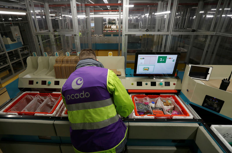 © Reuters. FILE PHOTO: A worker loads a grocery order into baskets at a "Pick Station" at the Ocado CFC (Customer Fulfilment Centre) in Andover