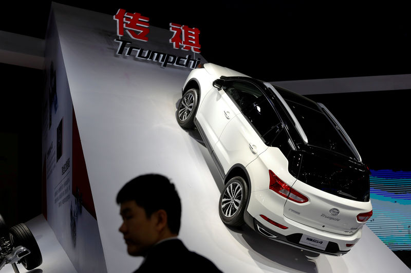 © Reuters. FILE PHOTO: Man stands in front of Trumpchi GS4 from GAC Group displayed at the auto show in Shanghai