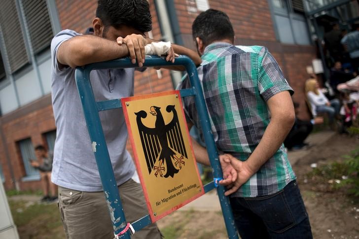 © Reuters. FILE PHOTO: Asylum seekers wait in front of the Federal Office for Migration and Refugees (BAMF) at Berlin's Spandau district