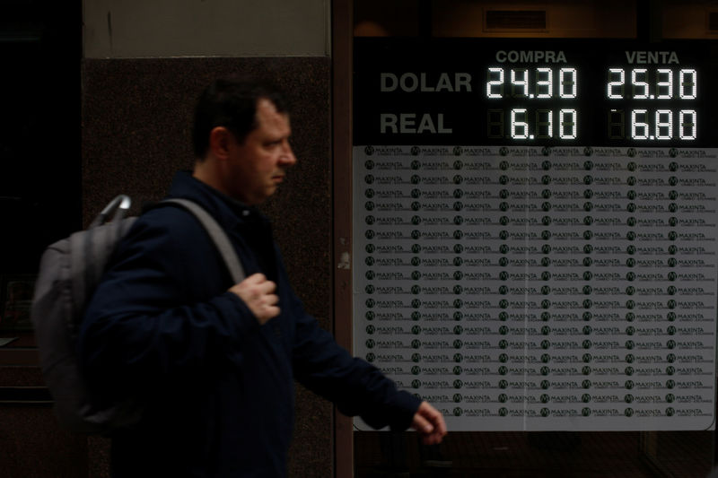 © Reuters. A man walks by an electronic board showing currency exchange rates in Buenos Aires
