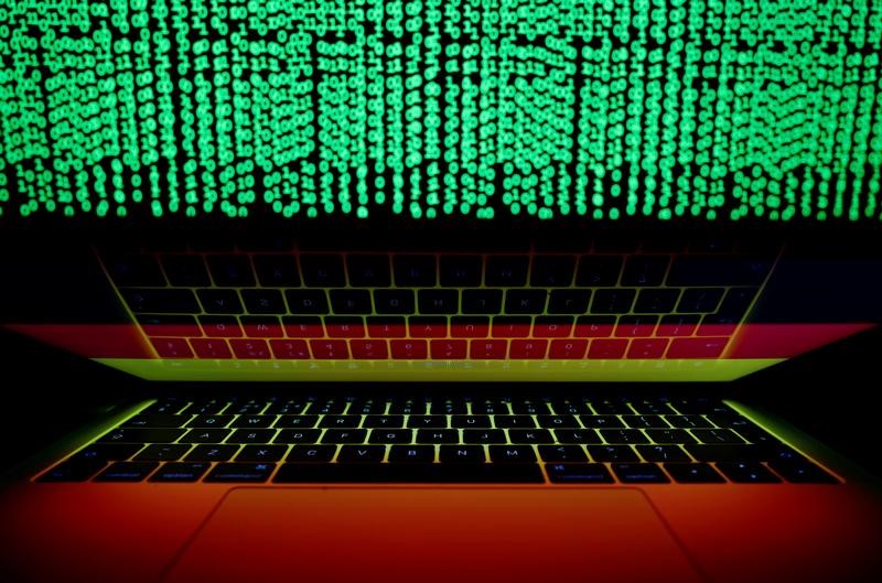 © Reuters. German flag is seen on the laptop screen in front of a computer screen on which cyber code is displayed, in this illustration picture