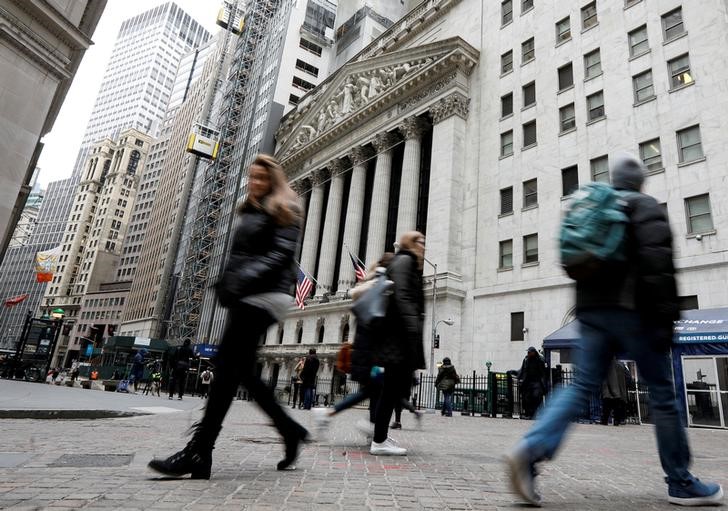 © Reuters. FILE PHOTO: People walk on Wall St. in front of the NYSE in New York